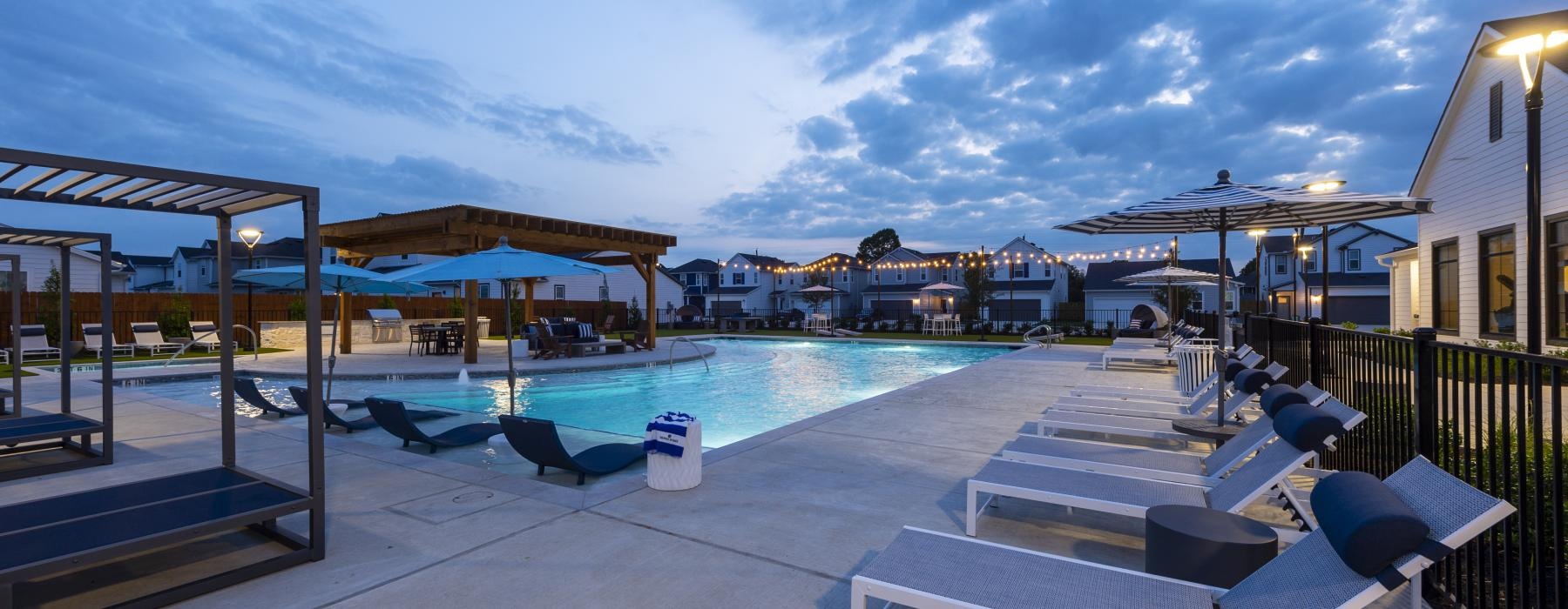 a pool with lounge chairs and umbrellas by it