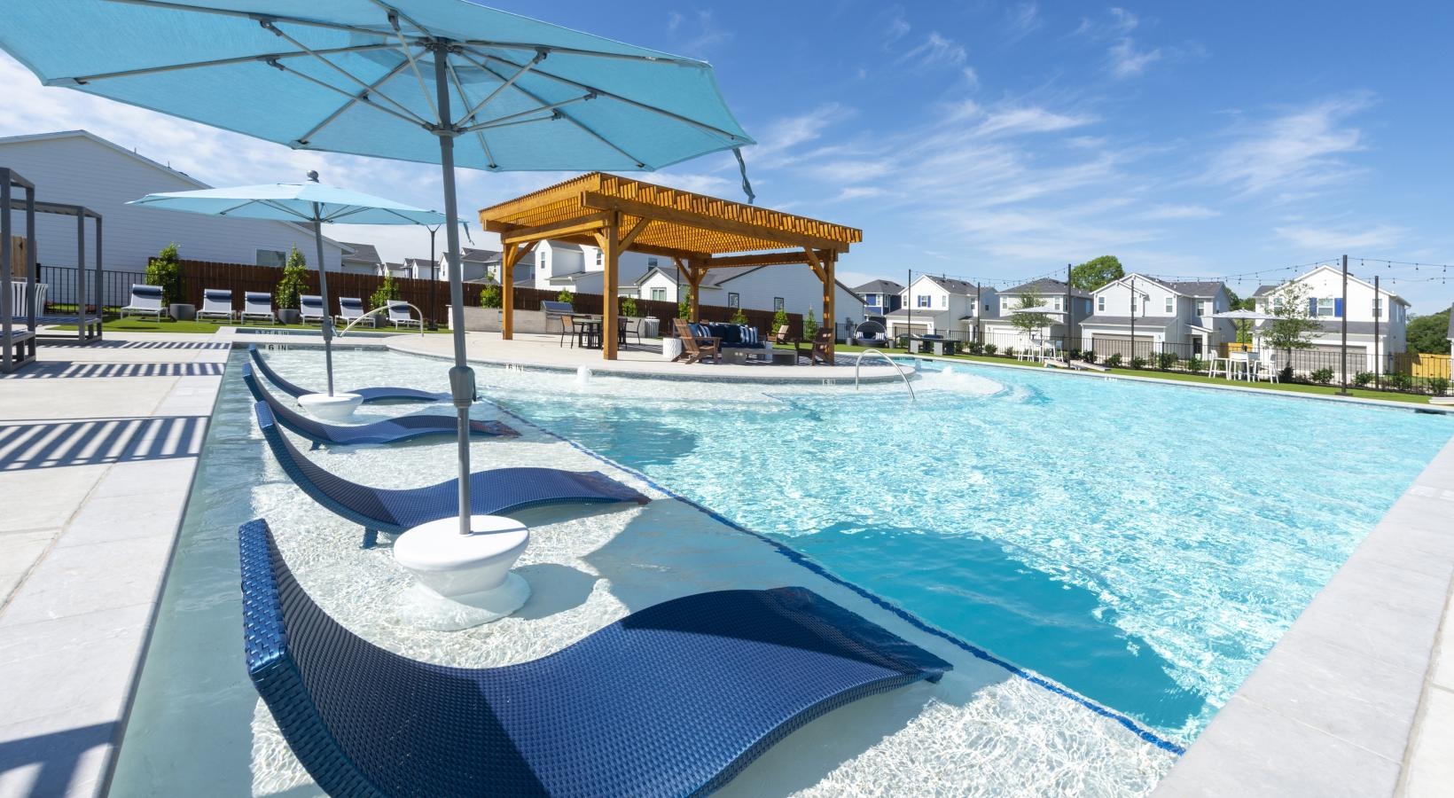 Shimmering resort-style pool a pool with a lounge chair and umbrellas by it